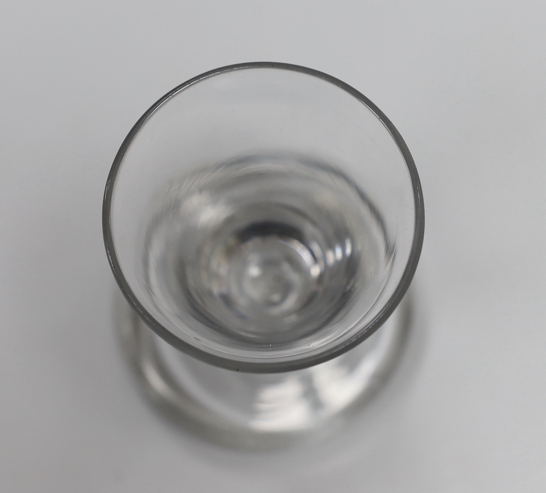 An English lead crystal drawn trumpet dram, c.1750, with striations and tool marks on a wide, heavy foot, 9.3cm high